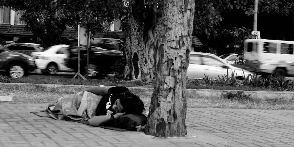 homeless person sleeping on side walk. reason we need social innovation